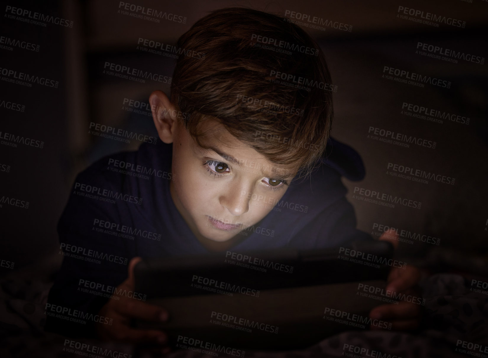 Buy stock photo Shot of adorable little boy using a digital tablet at night