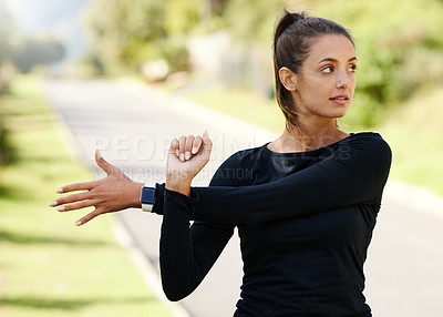 Buy stock photo Cropped shot of an attractive and athletic young woman warming up before starting her run outdoors