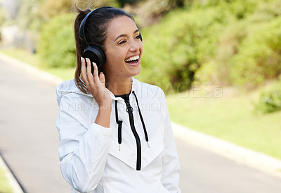 Buy stock photo Cropped shot of an attractive and athletic young woman listening to music while standing outdoors