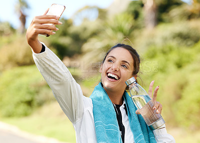 Buy stock photo Cropped shot of an attractive and athletic young woman taking selfies with her water bottle while standing outdoors