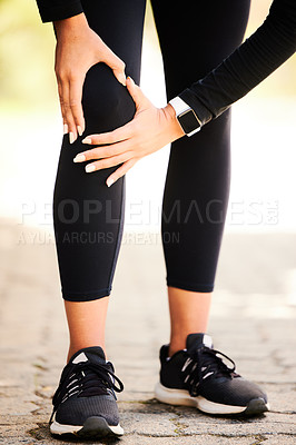 Buy stock photo Cropped shot of an unrecognizable and athletic woman holding her knee in discomfort while standing outdoors