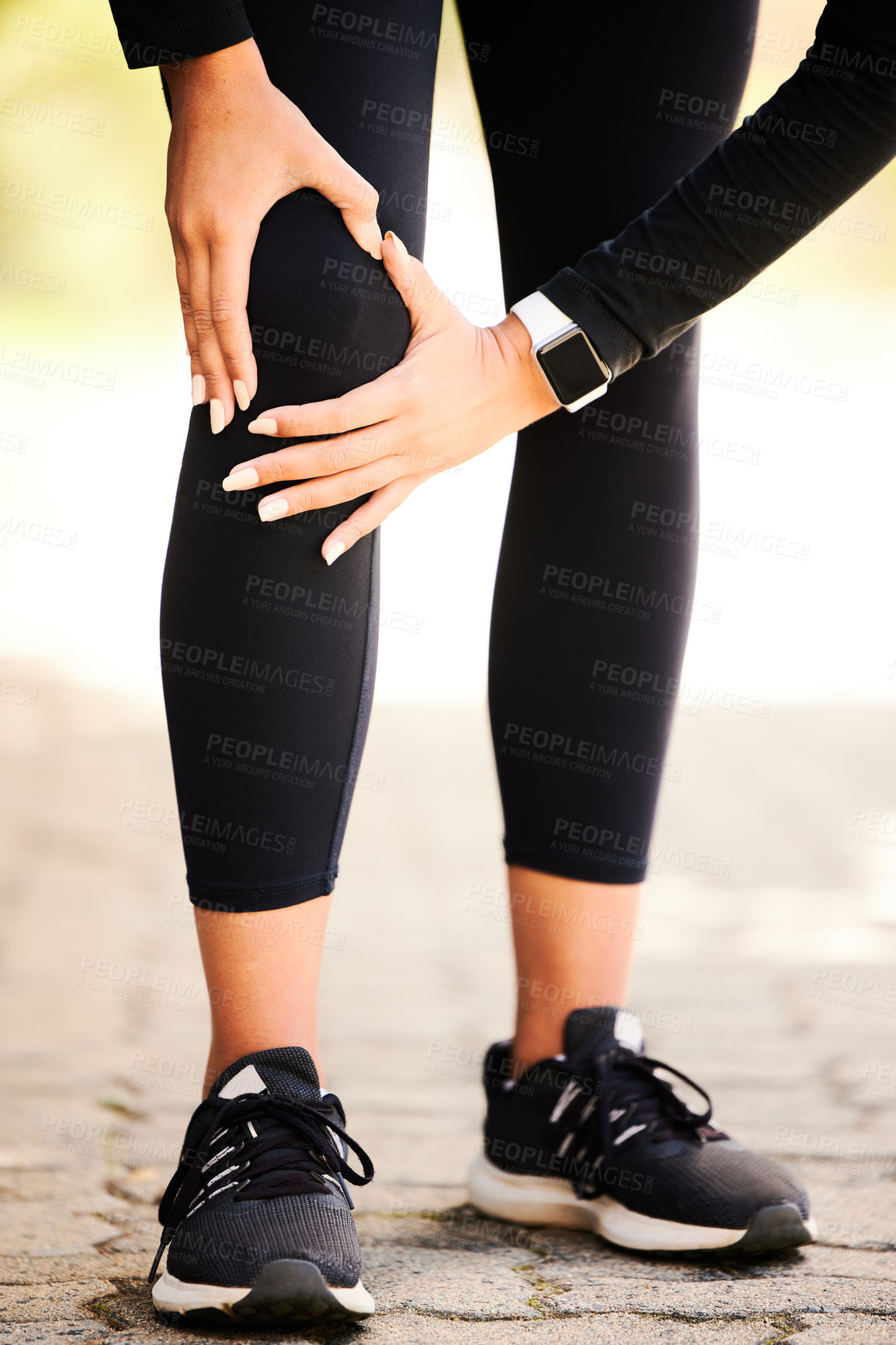 Buy stock photo Cropped shot of an unrecognizable and athletic woman holding her knee in discomfort while standing outdoors