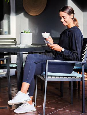 Buy stock photo Shot of a woman using her cellphone while sitting outside with a cup of coffee