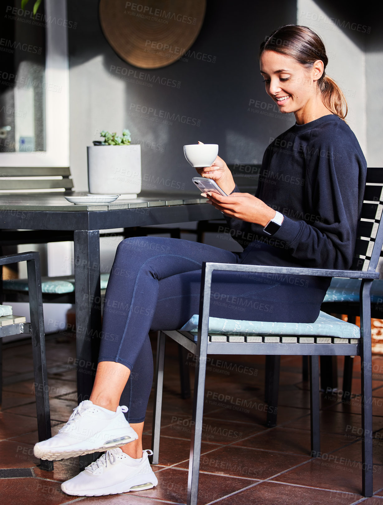 Buy stock photo Shot of a woman using her cellphone while sitting outside with a cup of coffee