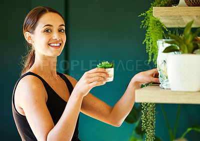 Buy stock photo Shot of a young woman decorating her house with plants