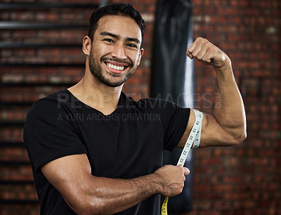 Buy stock photo Shot of a sporty young man measuring his biceps