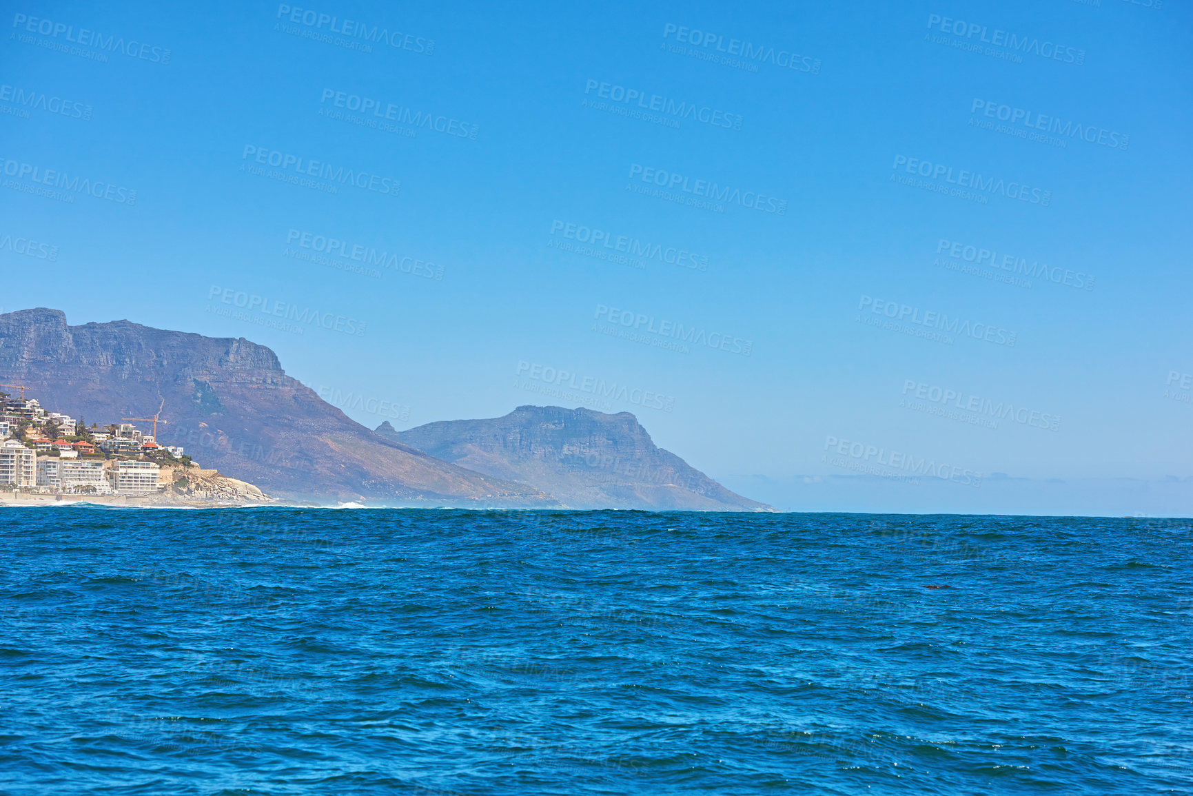 Buy stock photo The deep blue sea or vast expanse of the open ocean under clear blue sky copy space with Table Mountain in the background. Calm waters on a picturesque summer morning and view of the horizon 