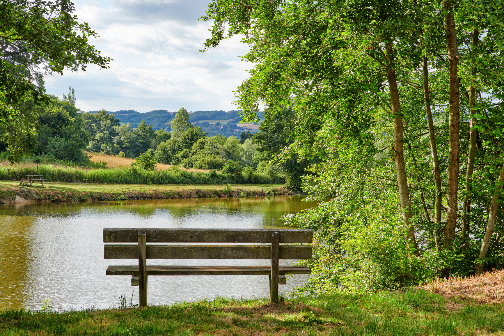 Buy stock photo Relaxing lake or park bench to enjoy zen landscape view of scenic pond or bay of water in nature reserve or botanical garden. Local wooden seating or furniture in serene, tranquil or calm countryside