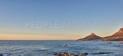 Buy stock photo Ocean view of sea water on rocky beach, mountains and a blue sky with copy space of Lions Head in Cape Town, South Africa. Calm tide, serene and tranquil scenery of relaxing mother nature at sunrise