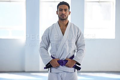 Buy stock photo Cropped portrait of a handsome young male martial artist standing with his hands on his belt in the gym