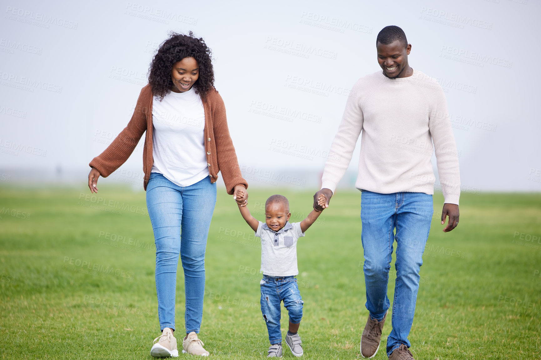 Buy stock photo Shot of a young couple walking with their son in a park