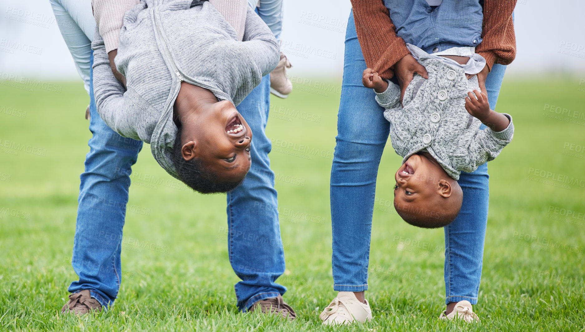Buy stock photo Shot of two children hanging upside down by their parents outside