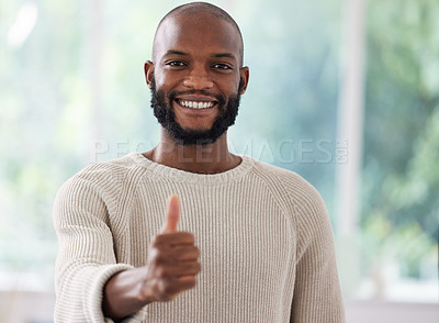 Buy stock photo Shot of a young man showing a thumbs up at home