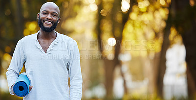 Buy stock photo Cropped portrait of a handsome young man holding his yoga mat while standing outside in the park