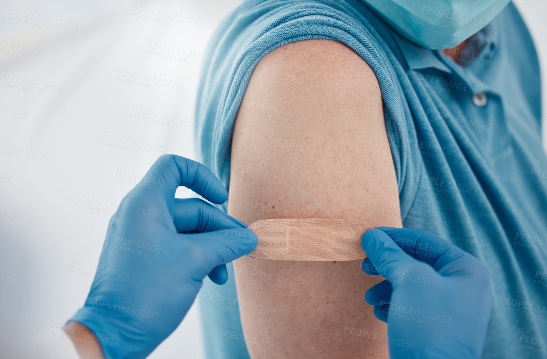 Buy stock photo Cropped shot of an unrecognizable male doctor placing a plaster on a patient's arm after giving him the covid 19 vaccine