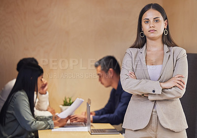 Buy stock photo Cropped portrait of an attractive young businesswoman standing with her arms crossed in the boardroom with her colleagues in the background