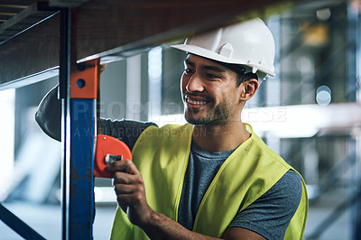 Buy stock photo Shot of a young builder using a measuring tape at a construction site