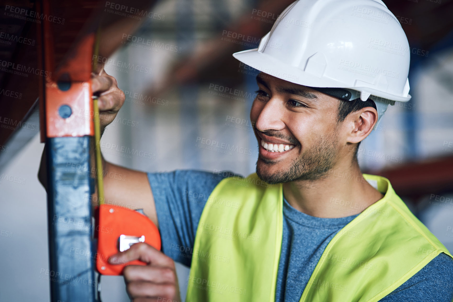 Buy stock photo Shot of a young builder using a measuring tape at a construction site