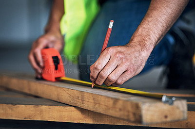 Buy stock photo Shot of a young builder using a measuring tape at a construction site