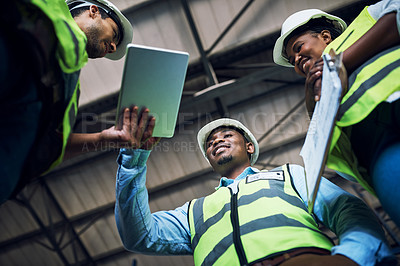 Buy stock photo Low angle shot of a group of builders using a digital tablet while working at a construction site