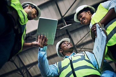 Buy stock photo Low angle shot of a group of builders using a digital tablet while working at a construction site