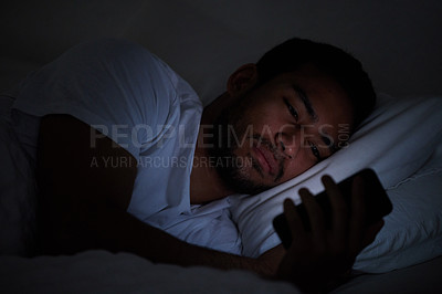 Buy stock photo Cropped shot of a man using his cellphone while lying in bed at night