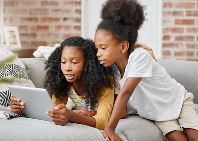 Buy stock photo Shot of two sisters using a digital tablet at home