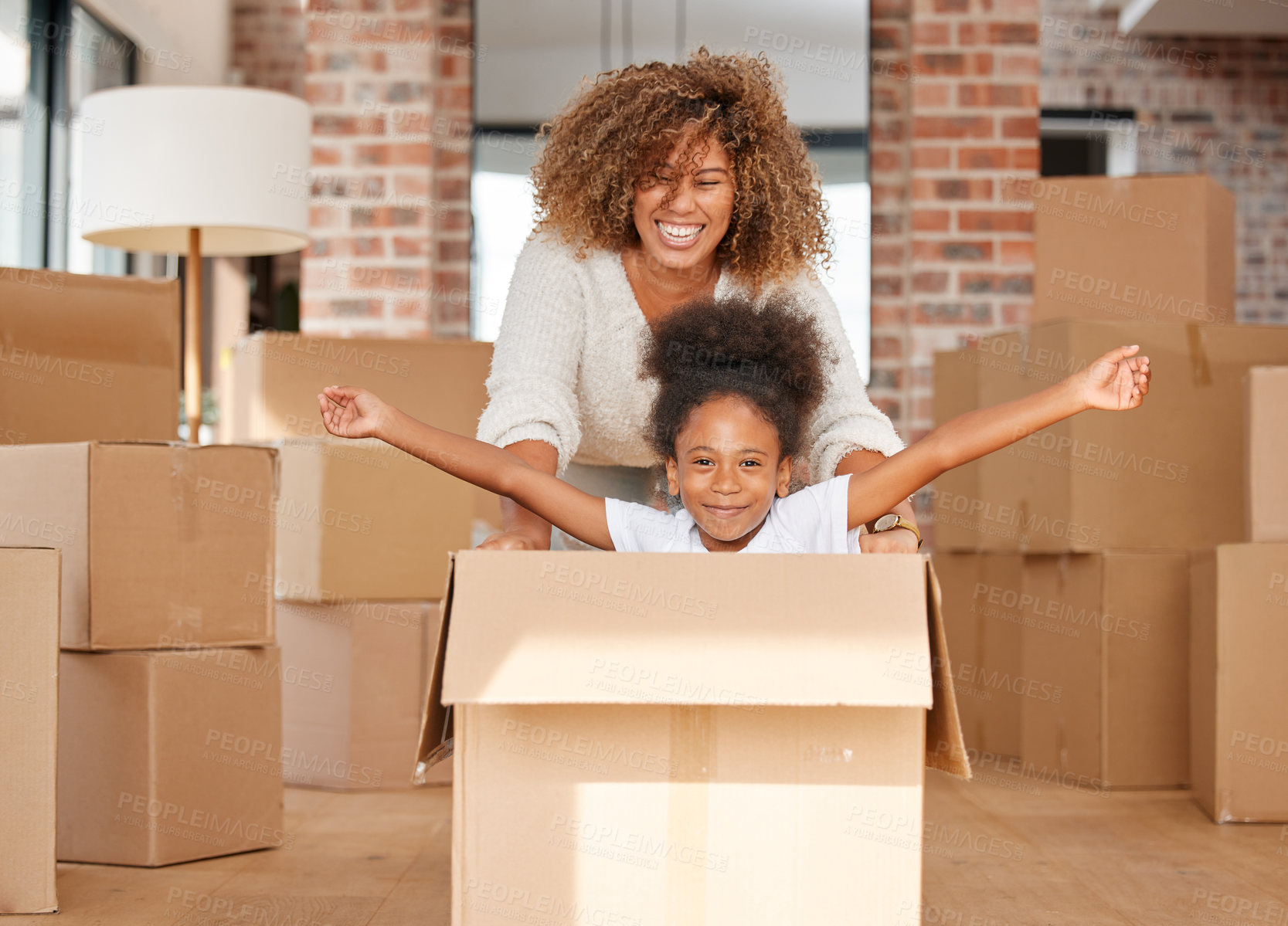Buy stock photo shot of a mother pushing her daughter in a box at home