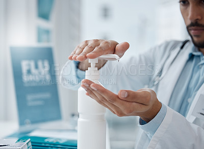 Buy stock photo Shot of a young doctor sanitising his hands in an office
