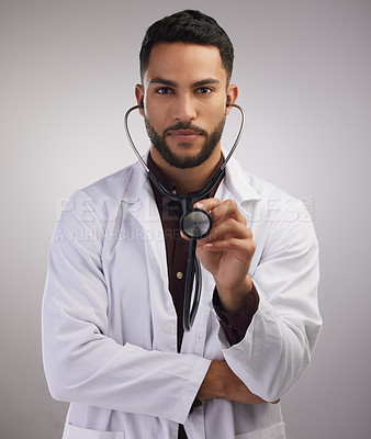 Buy stock photo Shot of a handsome young doctor standing alone in the studio and holding a stethoscope