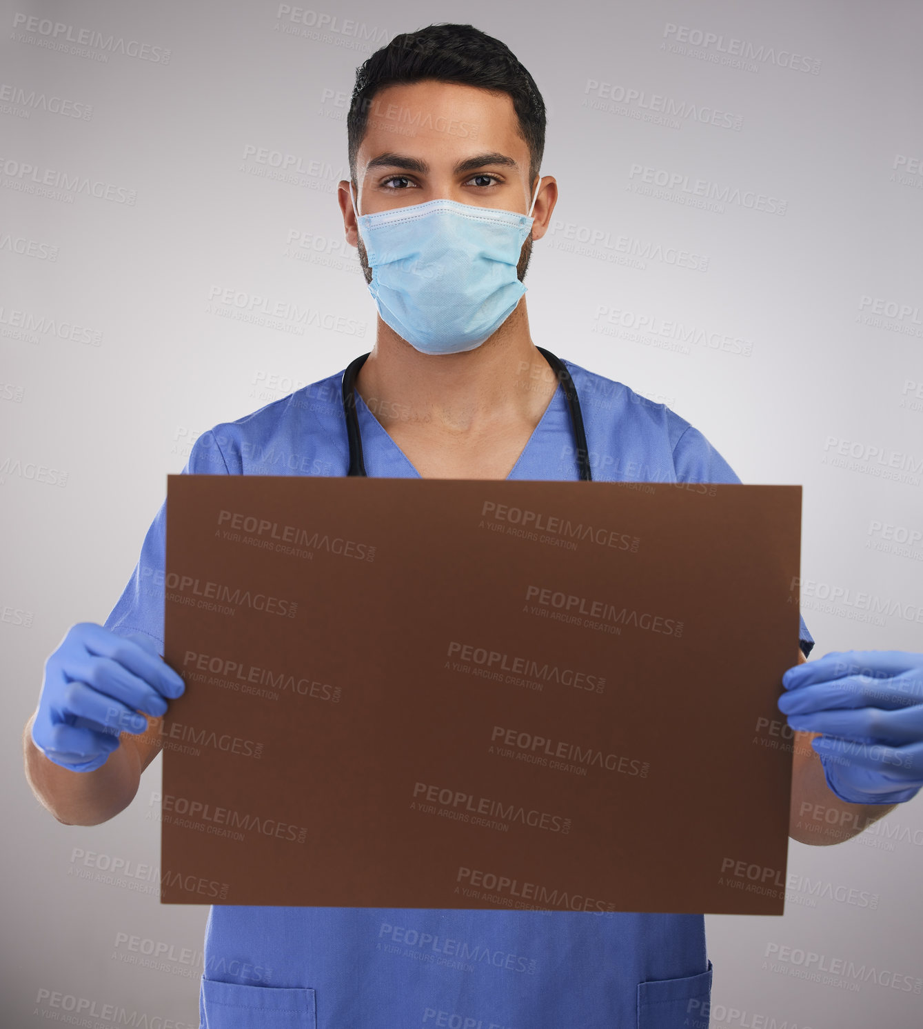 Buy stock photo Shot of a handsome young nurse standing in the studio and holding up a poster while wearing a face mask