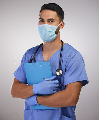 Buy stock photo Shot of a handsome young nurse standing alone in the studio and holding a clipboard while wearing a face mask