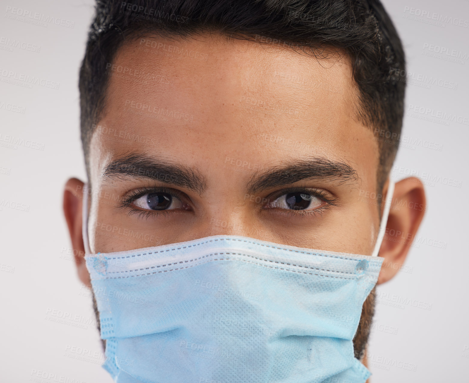 Buy stock photo Shot of a handsome young nurse standing alone in the studio and wearing a face mask