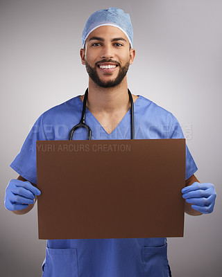 Buy stock photo Shot of a handsome young nurse standing alone in the studio and holding up a poster