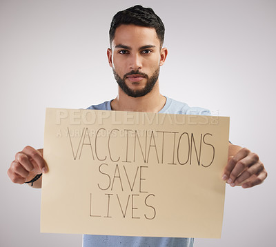 Buy stock photo Shot of a handsome young man standing alone in the studio and holding a poster after getting vaccinated