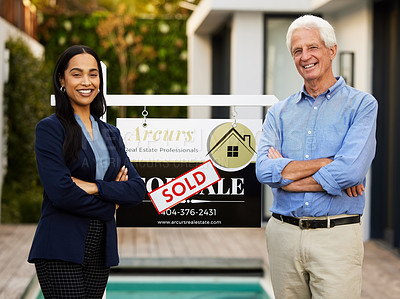 Buy stock photo Cropped portrait of an attractive young real estate agent and her male client standing with their arms crossed next to a sold sign outside of his newly purchased home