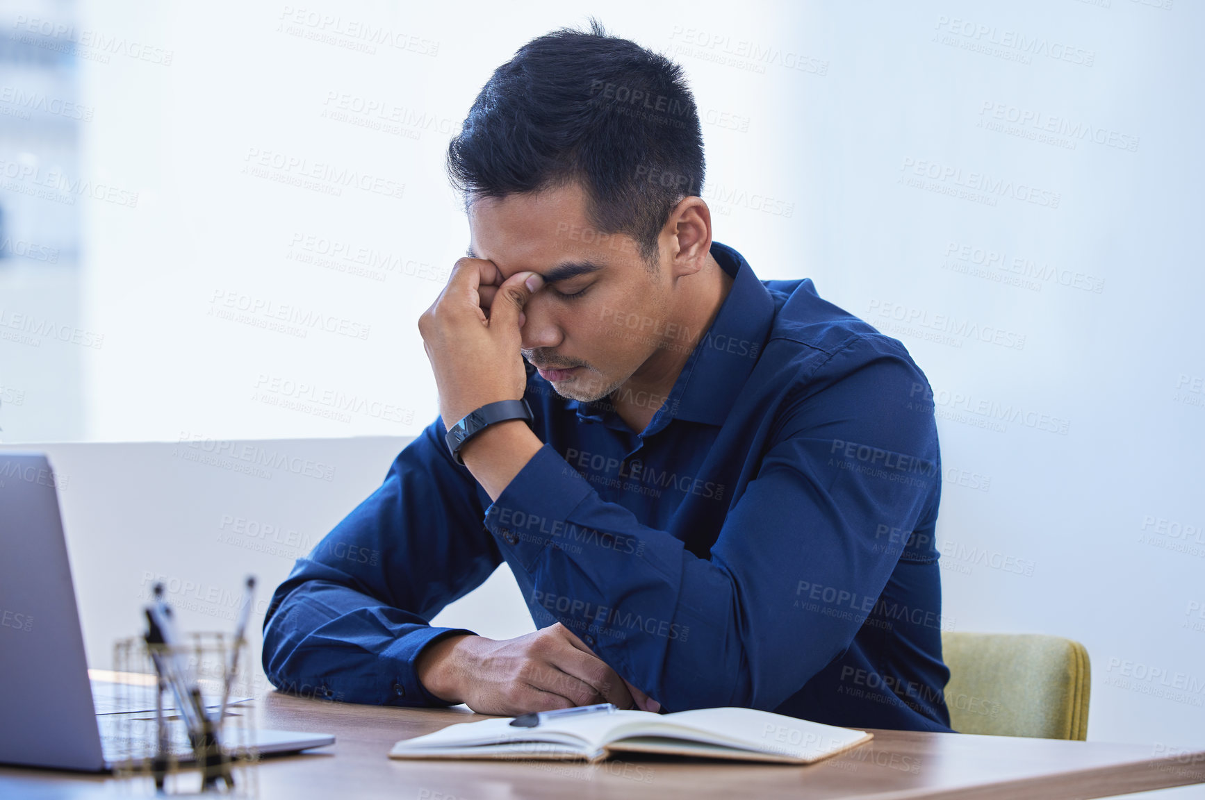 Buy stock photo Shot of a young businessman looking stressed out while working in an office