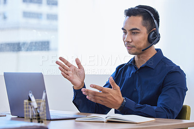 Buy stock photo Shot of a young businessman wearing a headset while using a laptop in an office