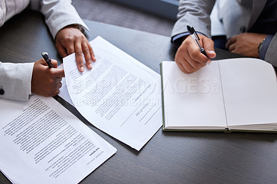 Buy stock photo Cropped shot of two people sitting together in an office with paperwork and a notebook