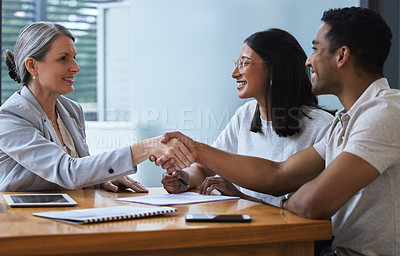 Buy stock photo Shot of a young couple sharing a handshake with a consultant they're meeting to discuss paperwork an office