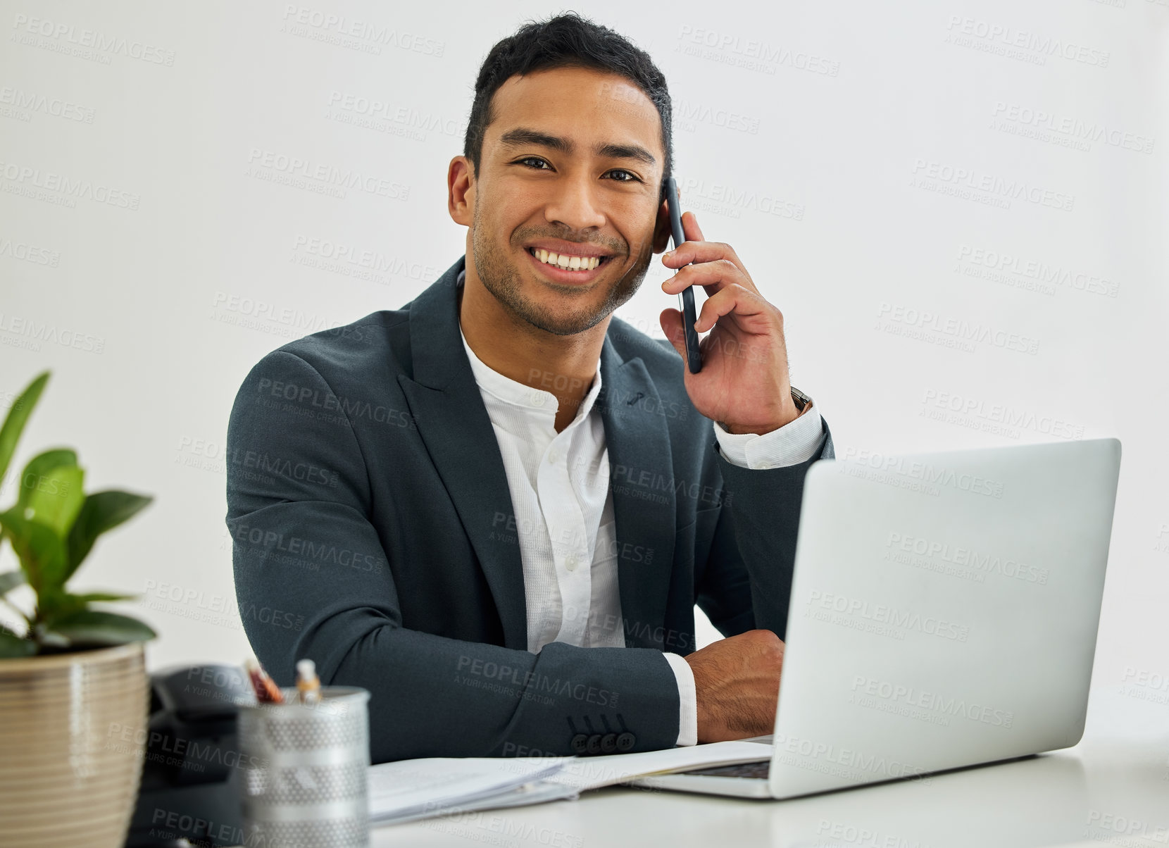 Buy stock photo Portrait of a businessman during a call on his smartphone at his desk in a modern office