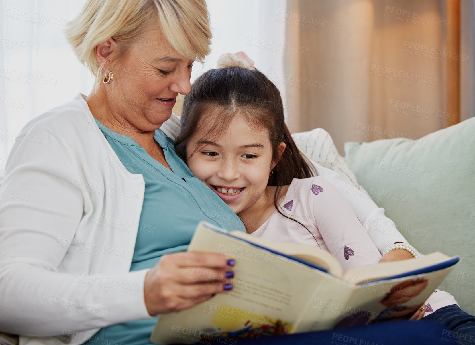 Buy stock photo Shot of a woman reading to her granddaughter at home