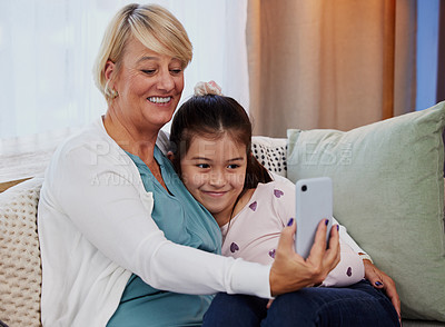 Buy stock photo Grandma, kid and smile with selfie on sofa for family bonding, care or memory in living room. Home, girl and elderly woman with digital photography for support, happiness or love in child development