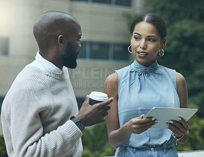 Buy stock photo Shot of two businesspeople using a digital tablet together outside an office