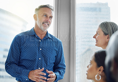 Buy stock photo Cropped shot of a handsome mature businessman addressing his colleagues while standing in the office