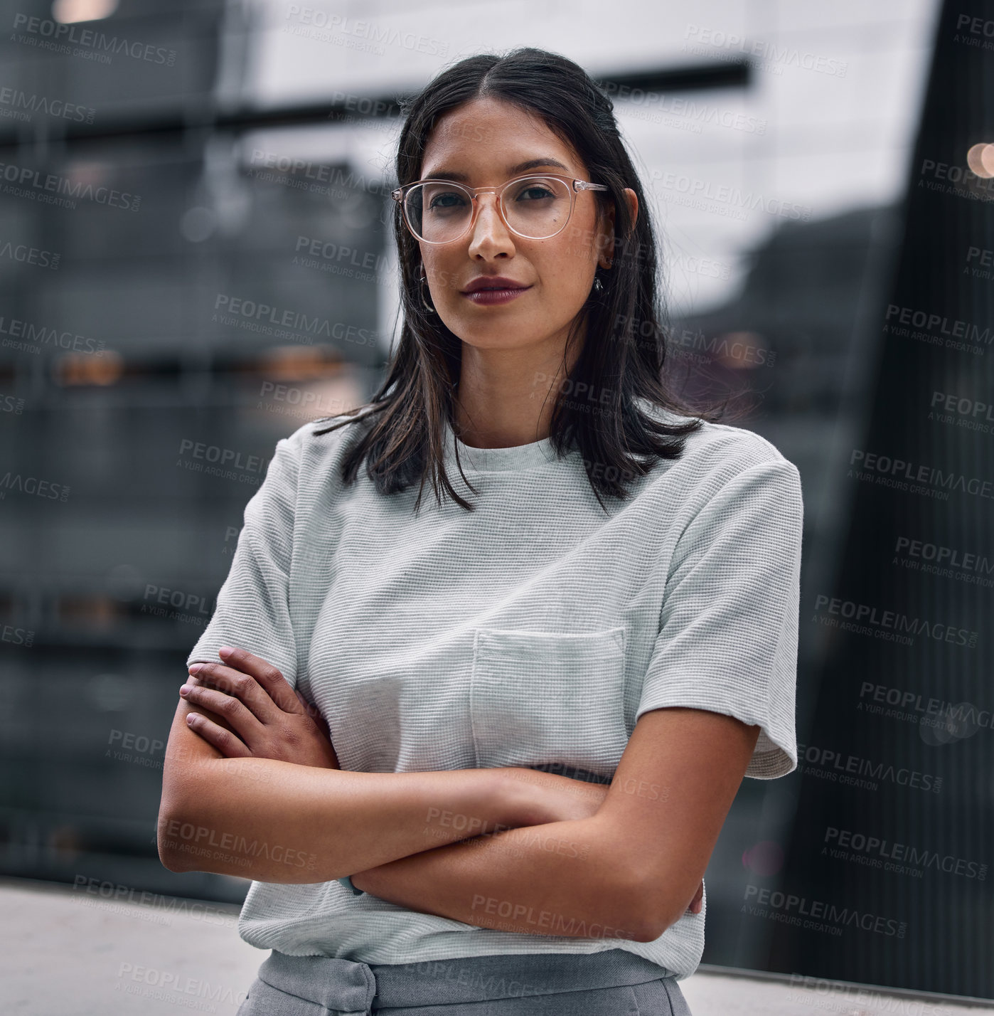 Buy stock photo Shot of an attractive young businesswoman standing alone in the office with her arms folded during a late shift