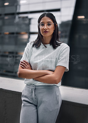 Buy stock photo Shot of an attractive young businesswoman standing alone in the office with her arms folded during a late shift