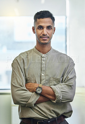 Buy stock photo Cropped portrait of a handsome young businessman standing with his arms folded in the office