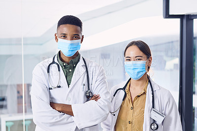 Buy stock photo Cropped portrait of two young doctors wearing masks while standing in the hospital