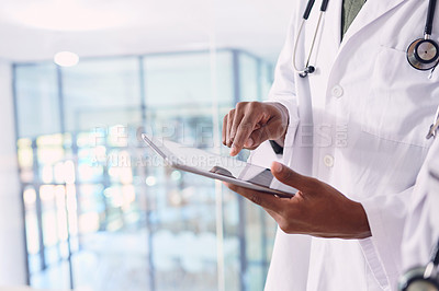 Buy stock photo Cropped shot of two unrecognizable doctors working on a digital tablet while standing in the hospital